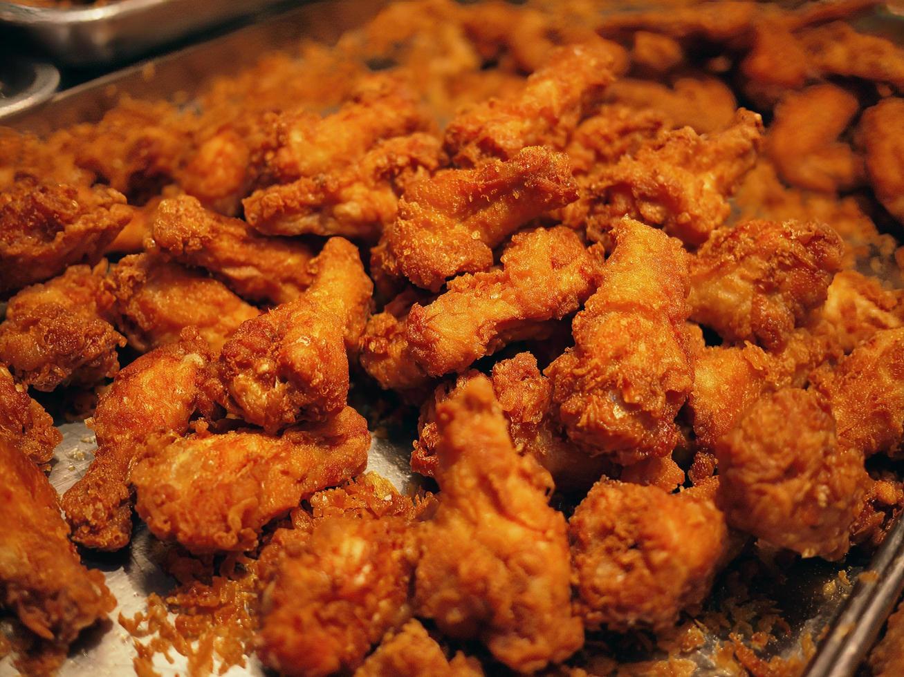 Pieza de muslo de pollo frito dorado al estilo local tailandés en el mercado nocturno de Tailandia foto