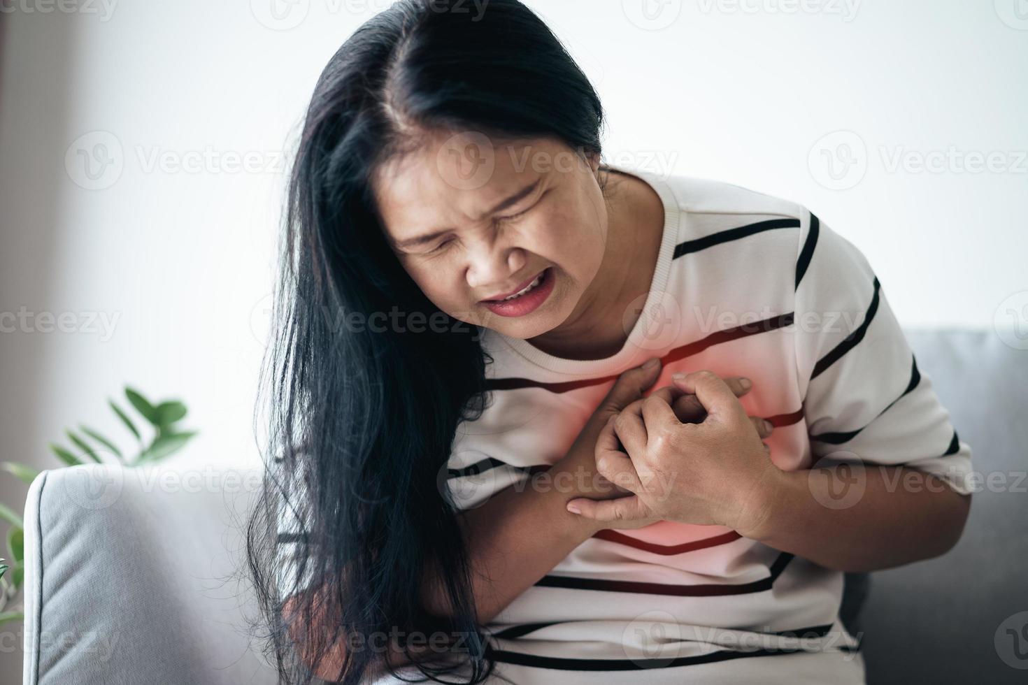 Closeup of Asian woman having heart attack. Woman touching breast and having chest pain. Healthcare And Medical concept. photo