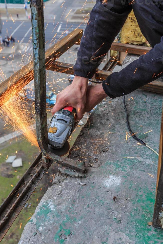 A worker cuts metal with a grinder. photo