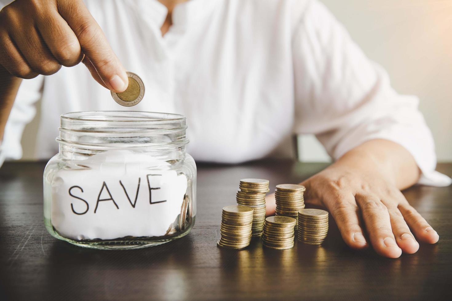 Woman hand putting money coin into glass photo