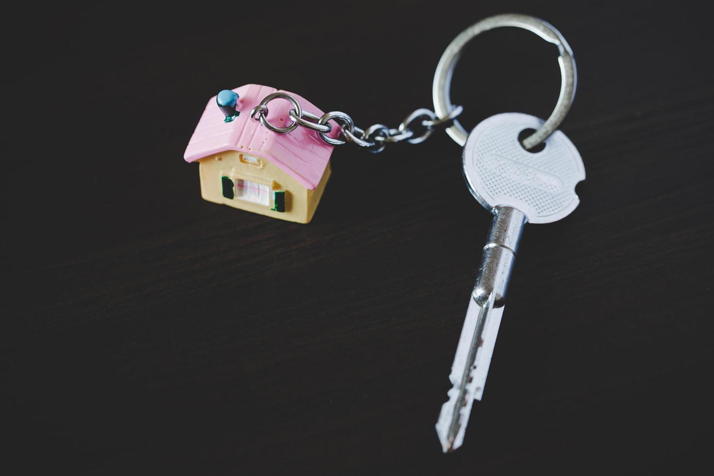 House key on a house shaped keychain resting on wooden photo