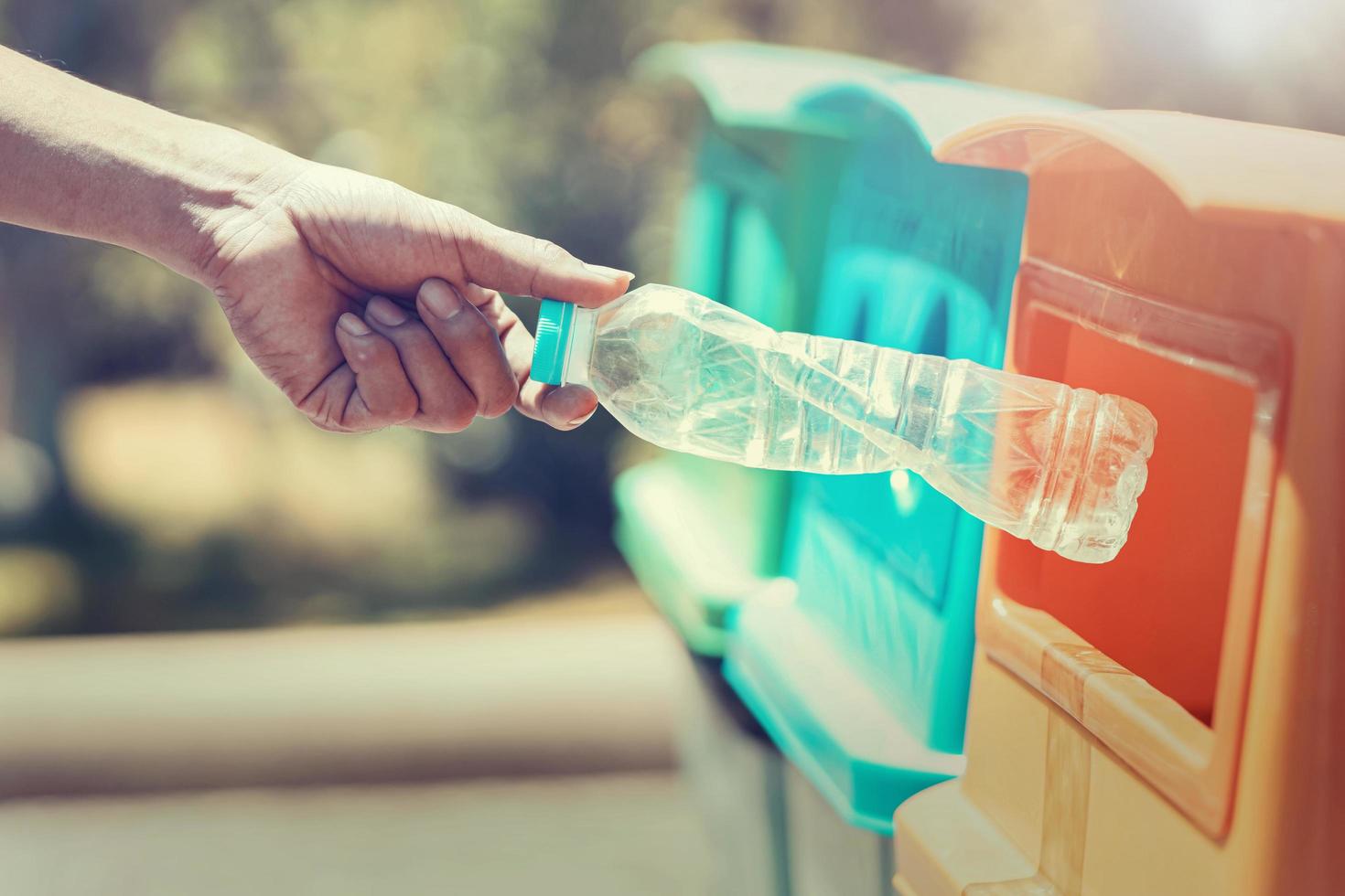 people hand holding garbage bottle plastic putting into recycle bin for cleaning photo