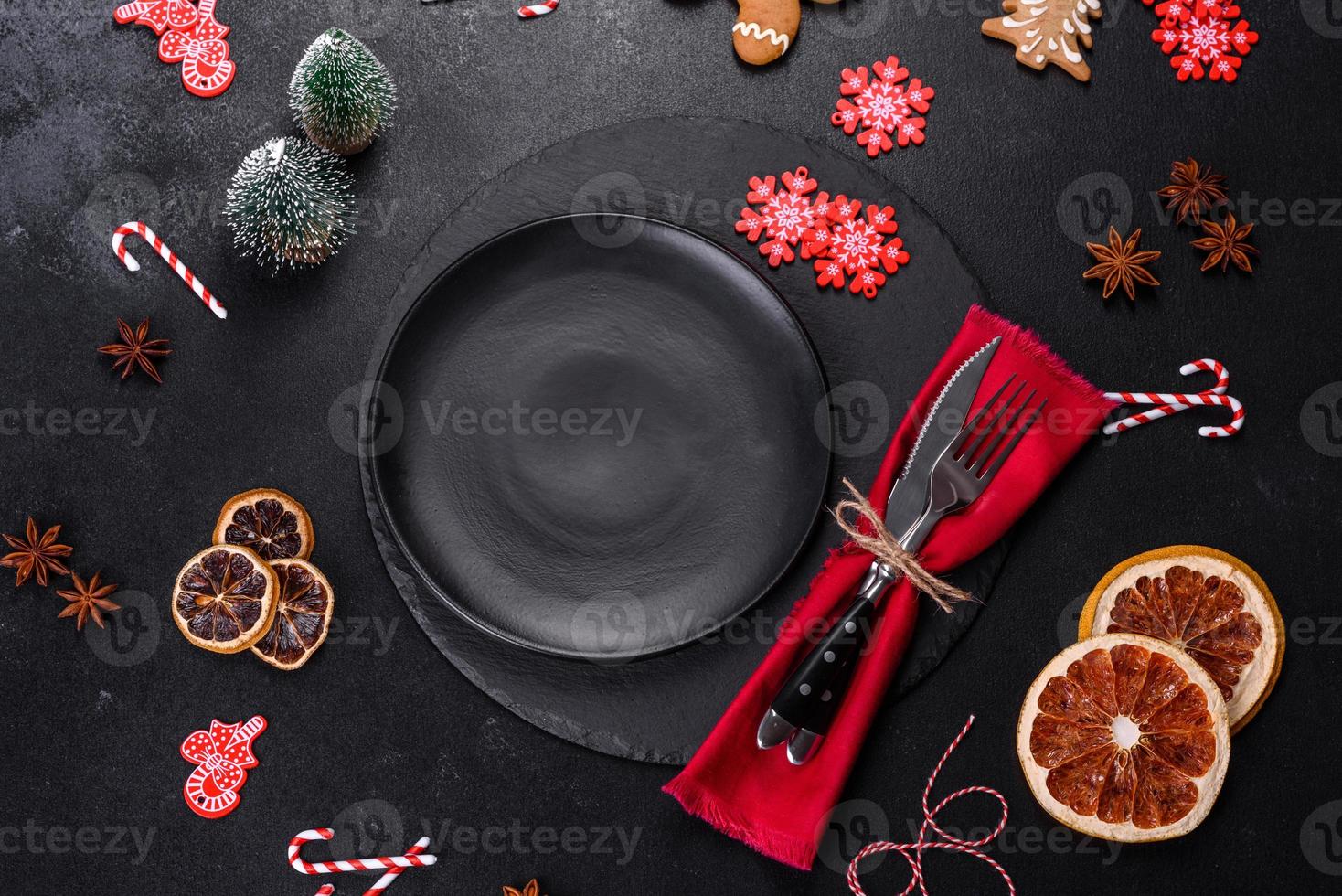 Christmas table setting with empty black ceramic plate, fir tree and black accessories photo