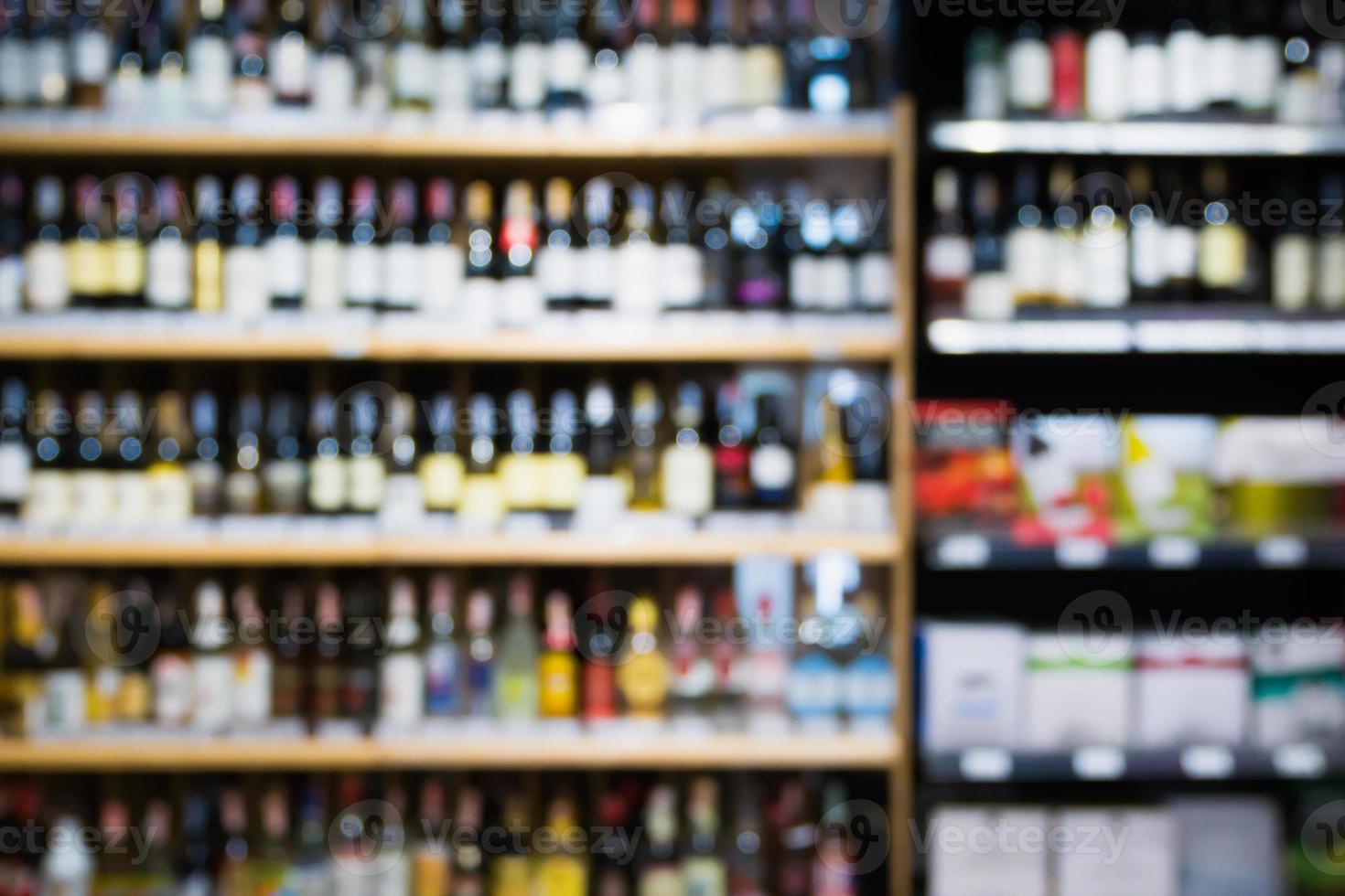 Desenfoque abstracto de botellas de vino en estantes de alcohol de licor en el fondo del supermercado foto