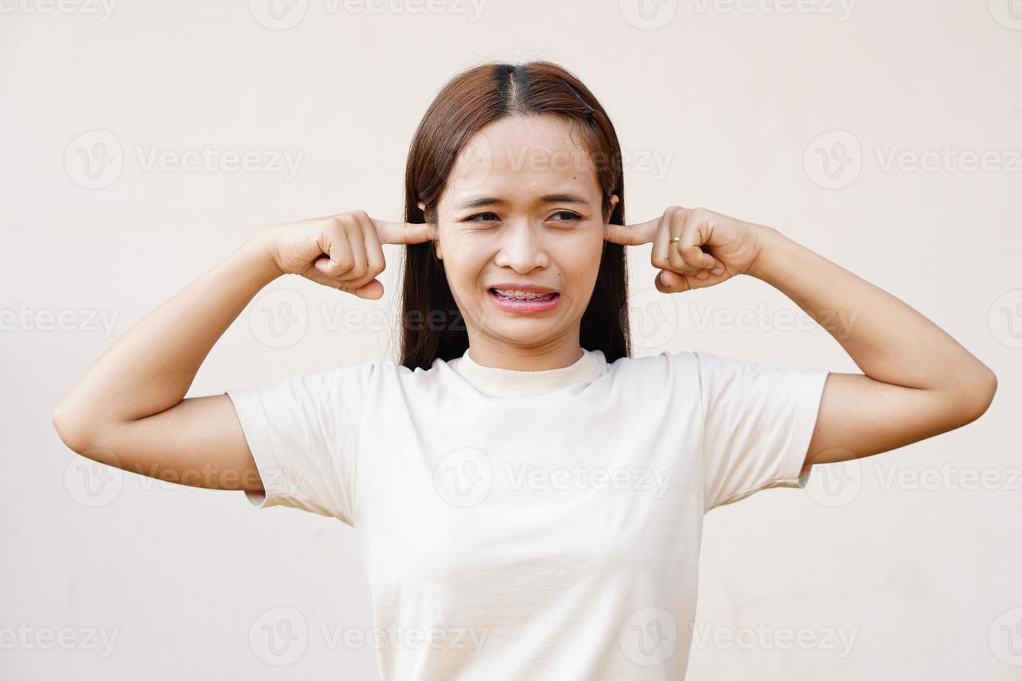 mujer asiática tapándose los oídos con las manos foto