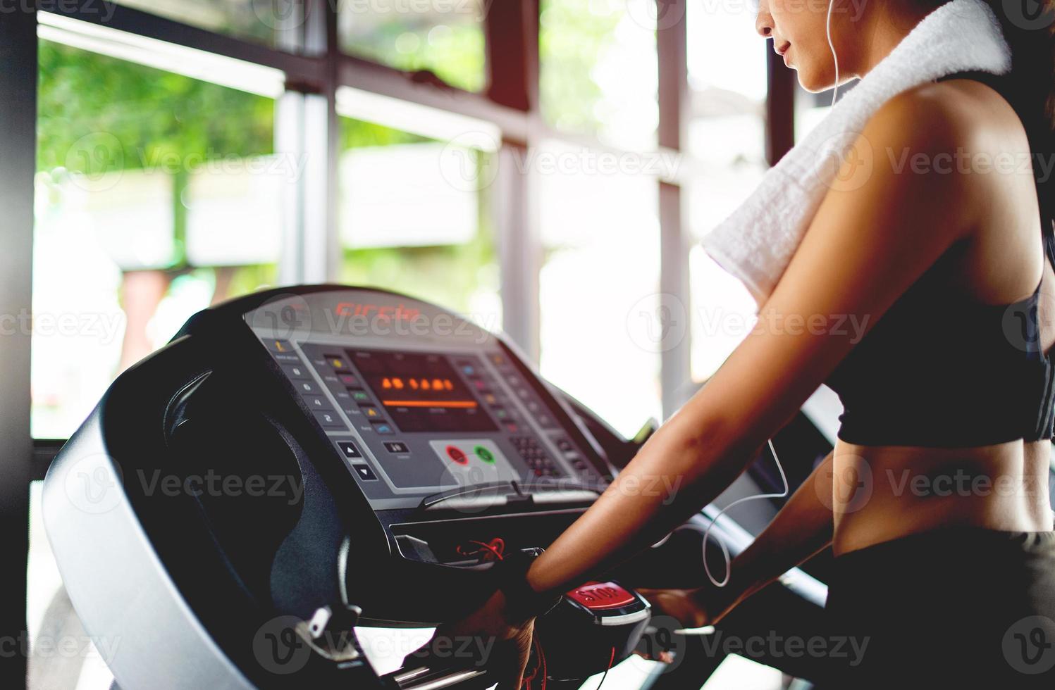 girl in the gym working out on an automatic treadmill use a cell phone Listening to music with white headphones and using a digital heartbeat timer. systematic exercise her vacation relaxation photo