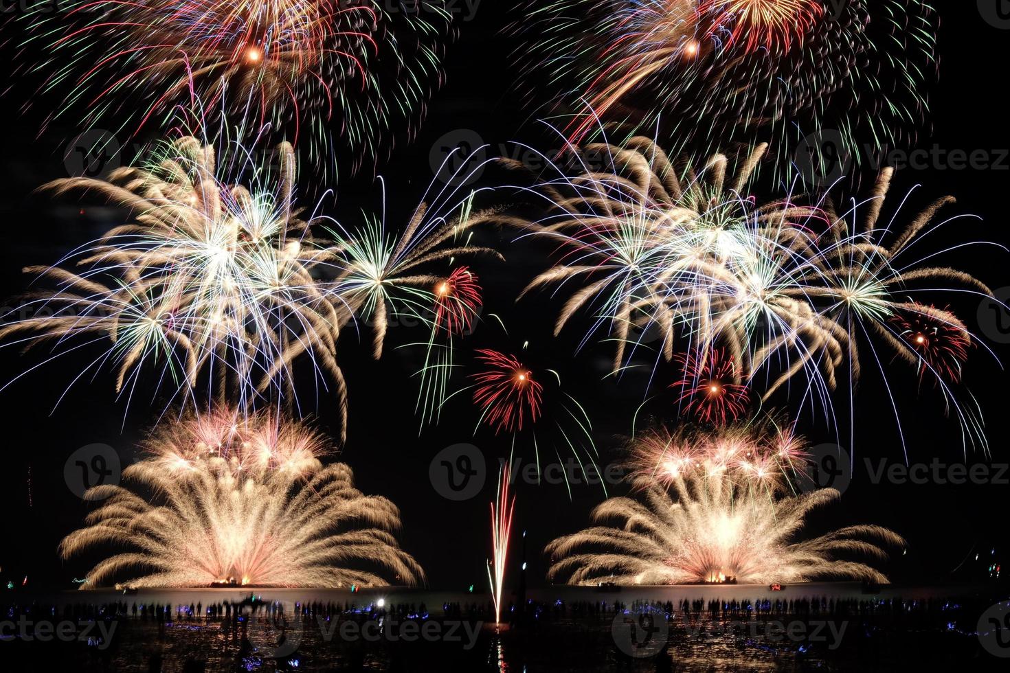 los fuegos artificiales festivos se iluminan sobre el cielo nocturno en la playa. colorida celebración de fuegos artificiales sobre fondo oscuro. foto