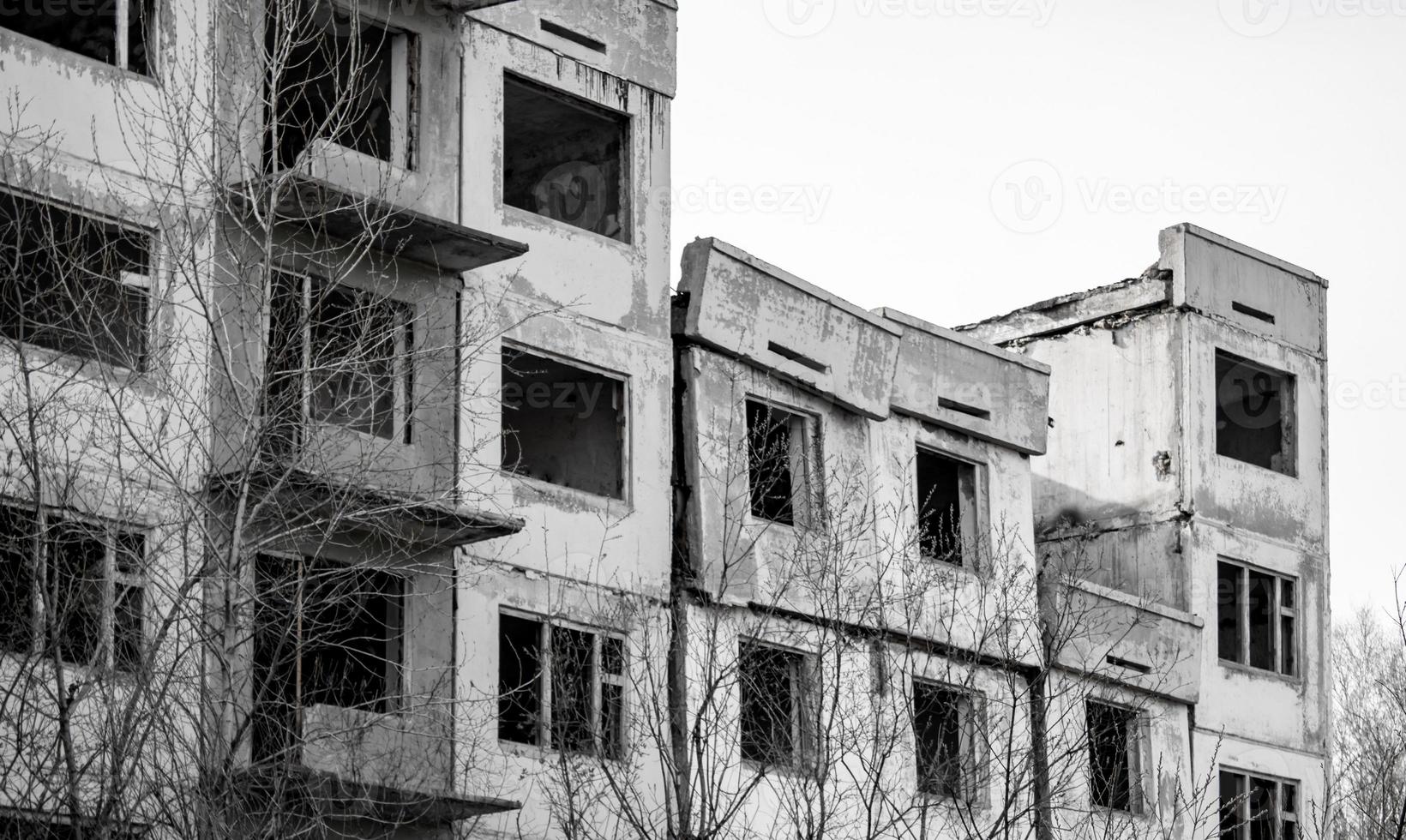 Dilapidated residential building with empty windows, collapsed roof, collapsed roof. Black and white photo