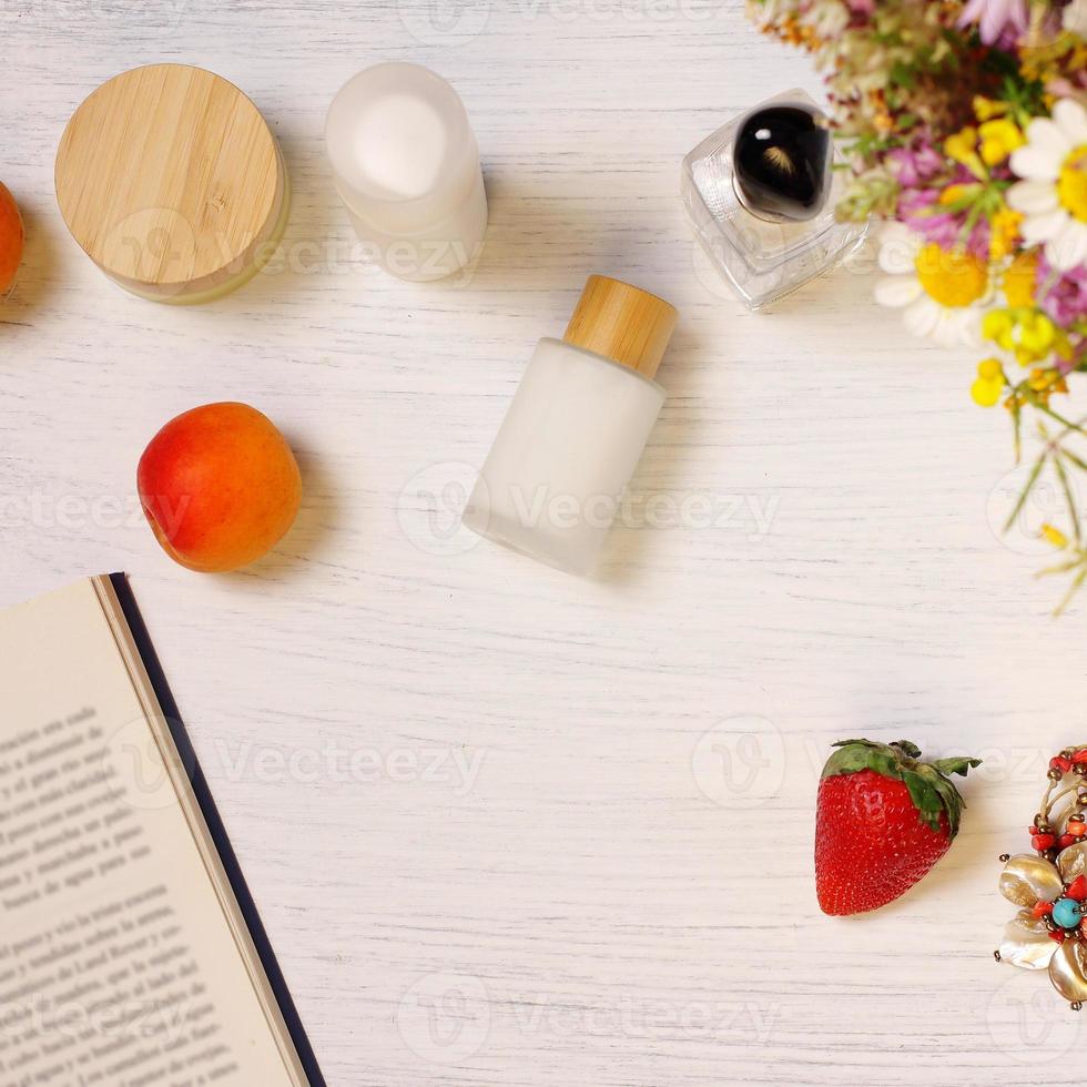 Cosmetic bottles, fruit flowers and book on table, lifestyle staging photo