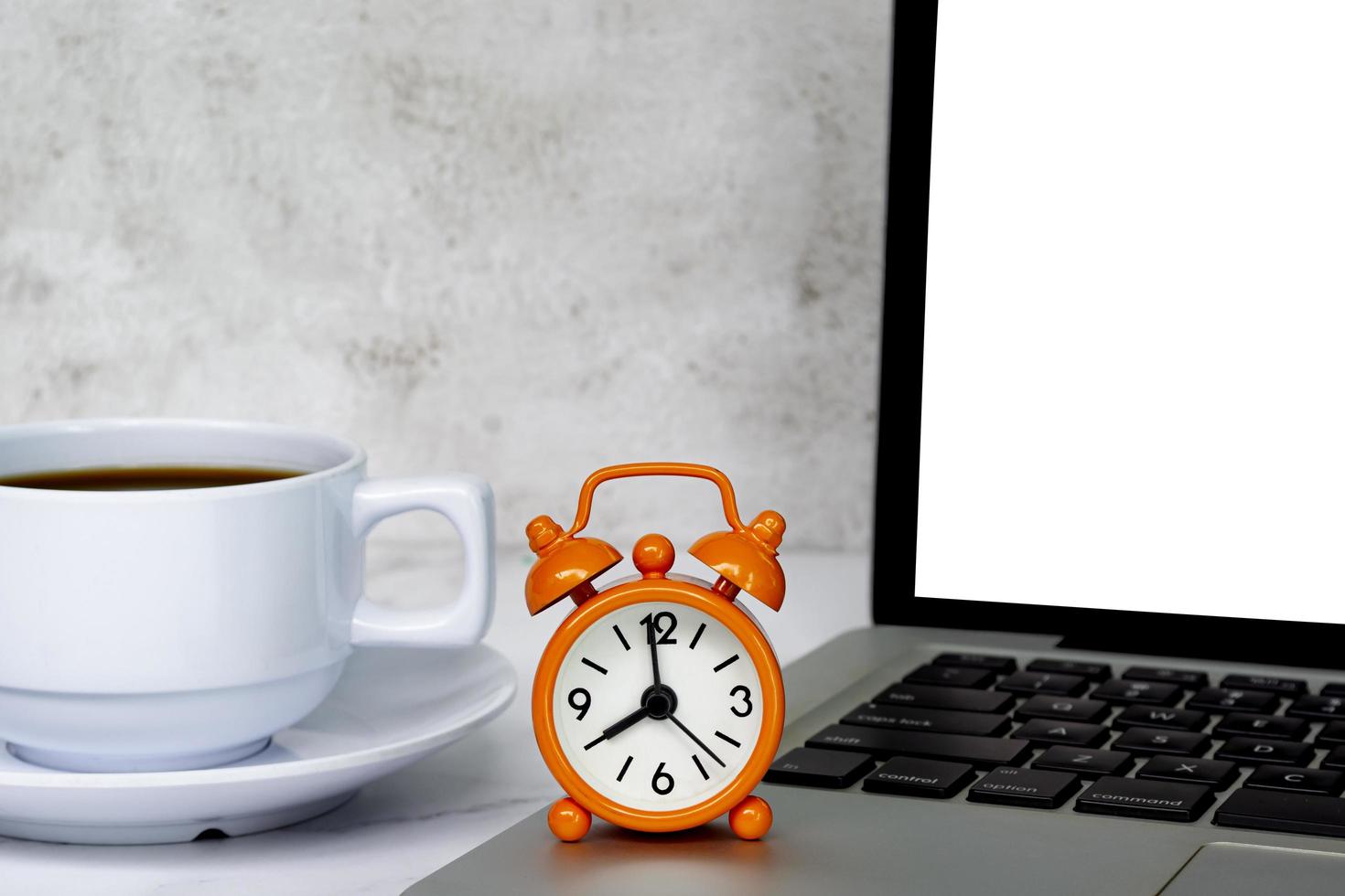 Alarm clock on laptop with coffee cup on a table. The clock set at 8 o'clock. photo