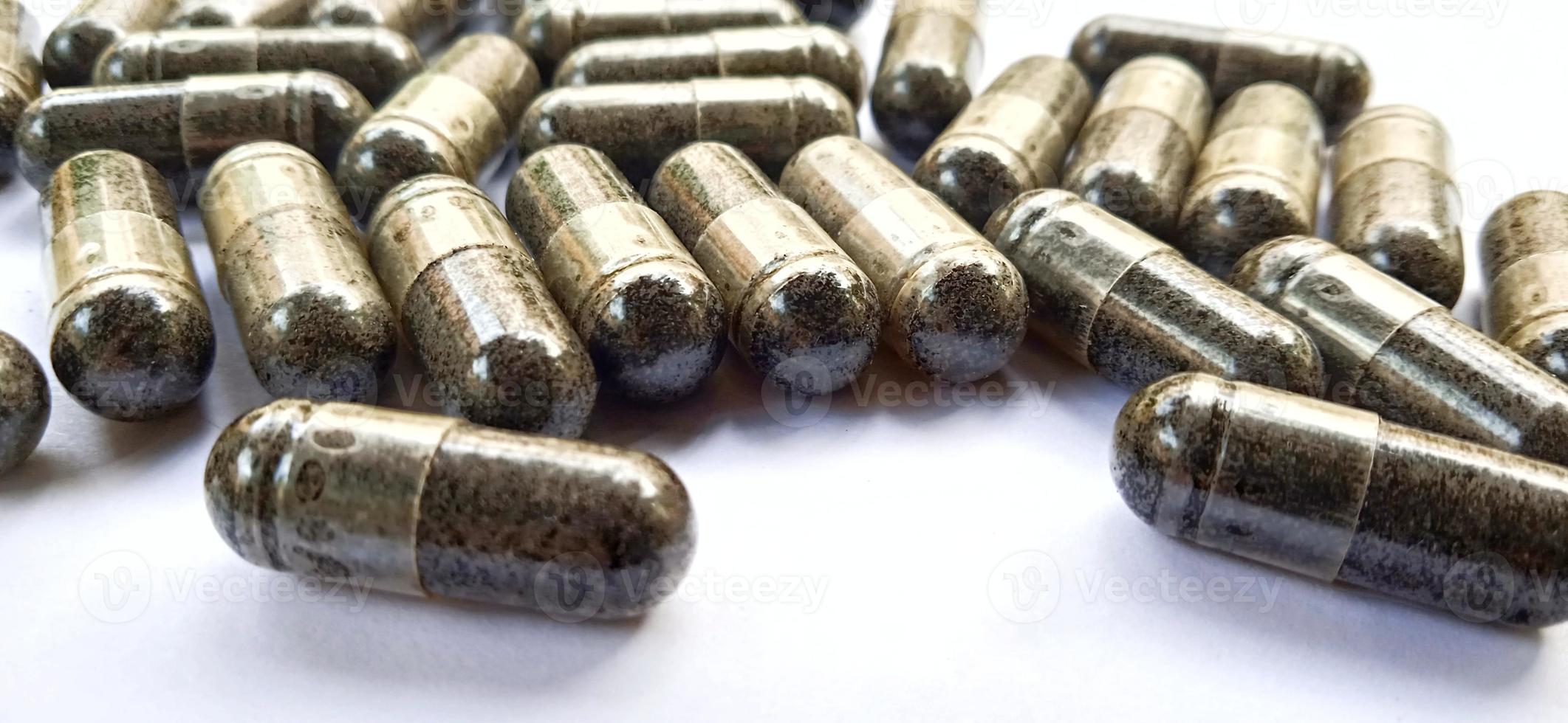Herbal medicine black cumin capsules with negative space isolated on the gray white studio background. Nigella sativa. Suitable for promotion of health industry and company. photo