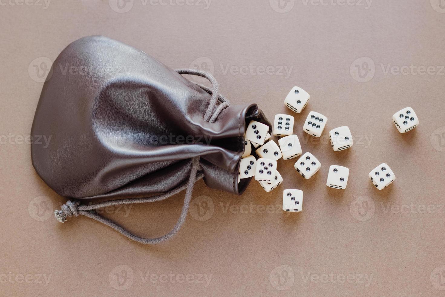 Set of gaming dice rolled out of leather bag on brown background. Concept with copy space for games, game board, role playing game, dnd, risk, chance, good luck or gambling. Toned image top view. photo