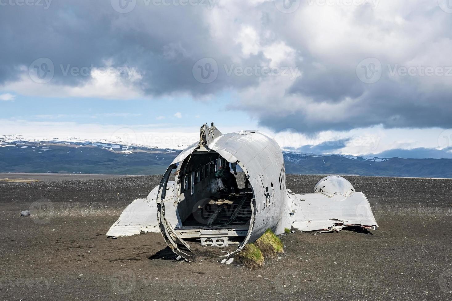 Broken airplane wreck at black sand beach in Solheimasandur against cloudy sky photo