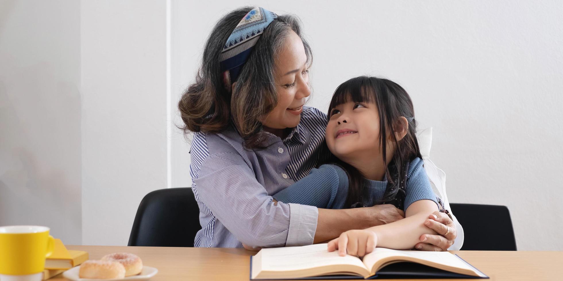 happy asian family grandmother reading to granddaughter child book at home photo