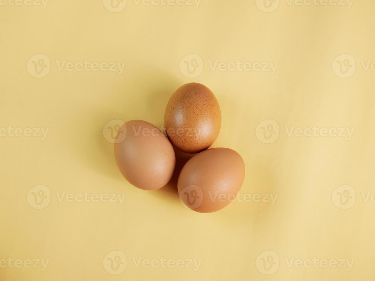 Eggs are laid in groups of three, eggshells with different patterns. Shot in a studio with light and shadows against an eggshell colored background. photo