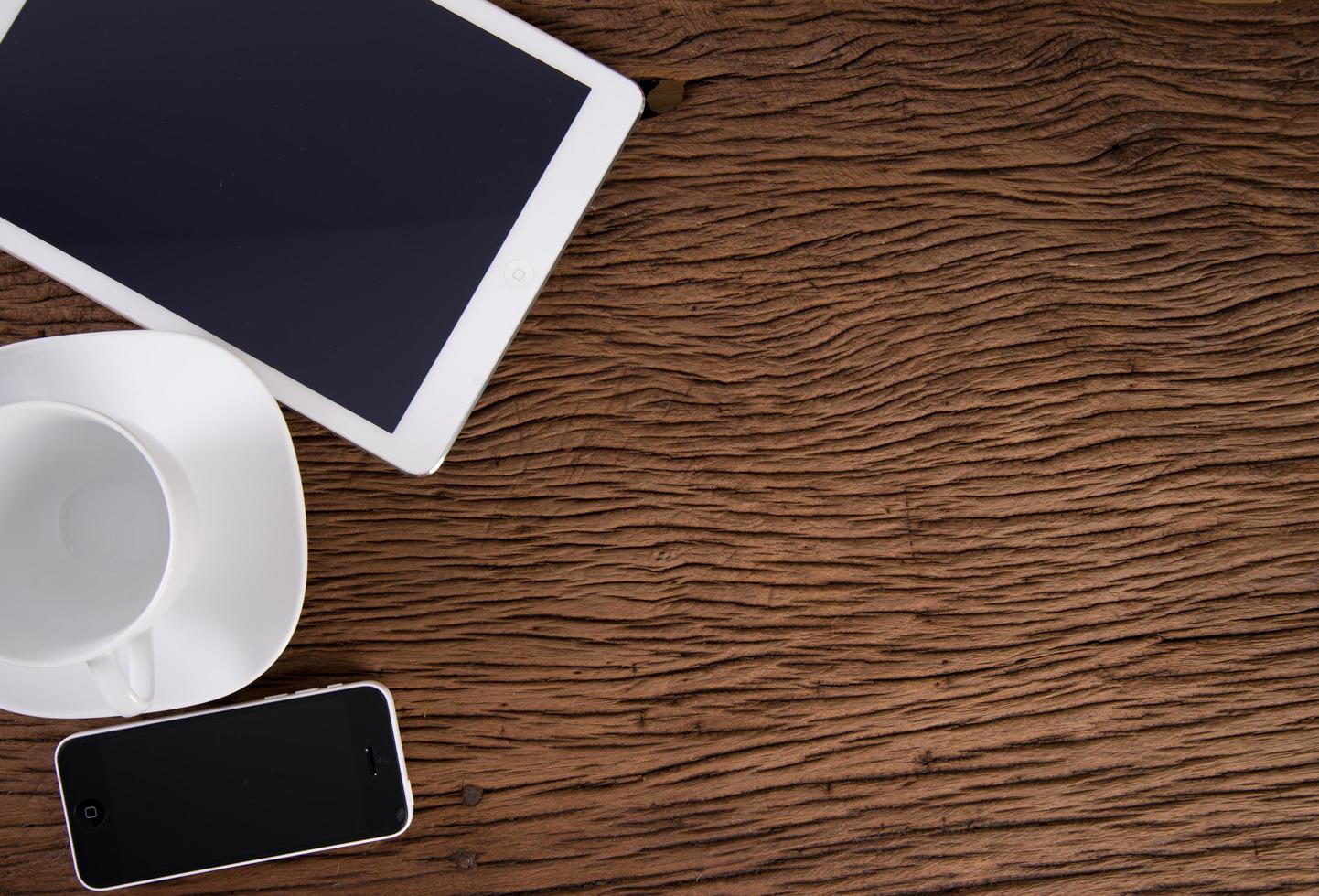 Digital tablet computer and white smart phone with emtry cup of coffee on old wooden background photo