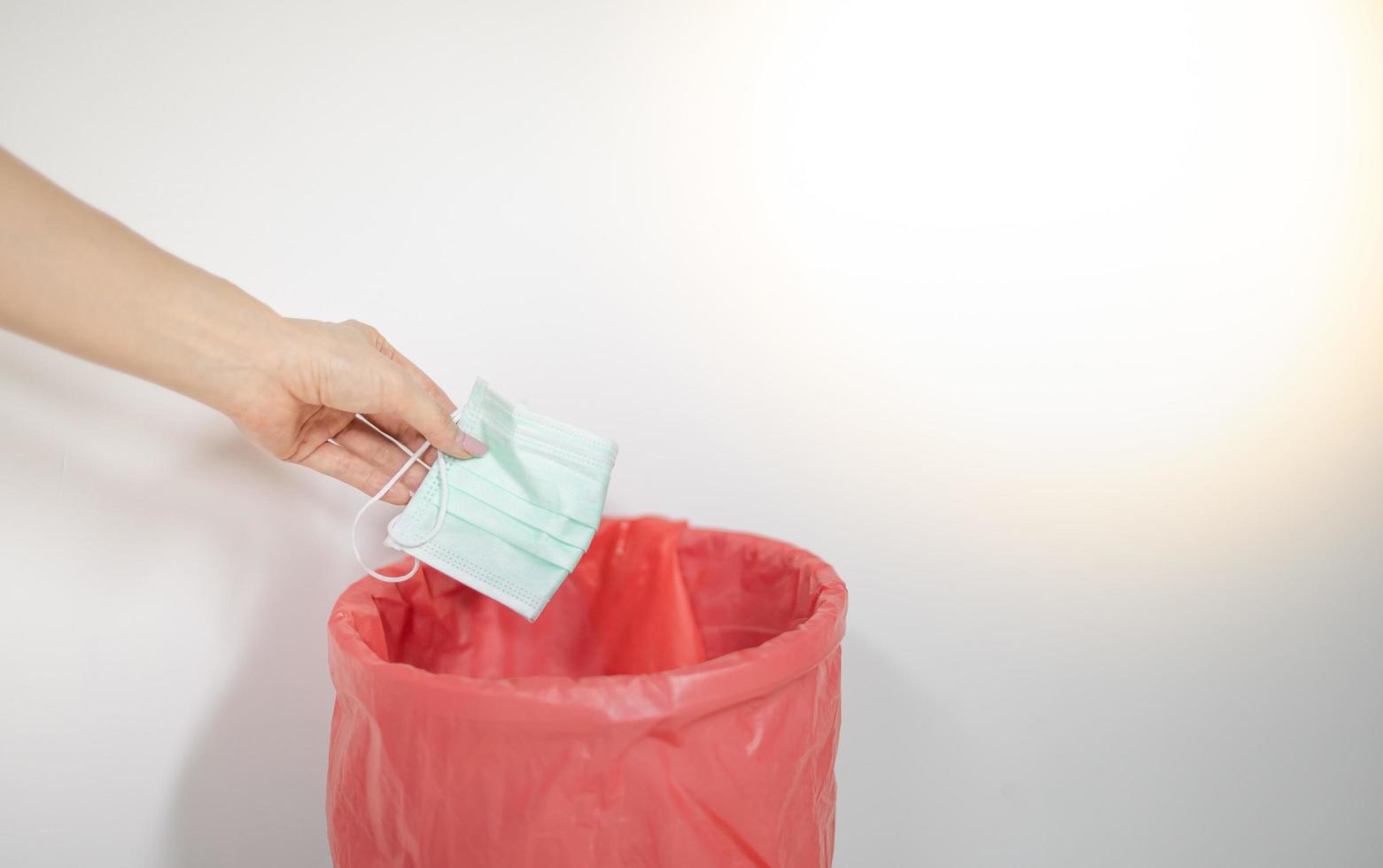 Female throw surgical mask after use throwing  in dangerous trash to prevent virus from spreading from mask to trash can and to people. photo