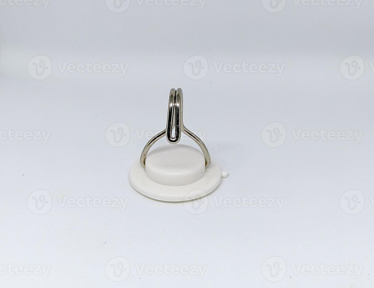 a white hanger or Hook made of plastic and iron with insulation to stick to the wall behind it isolated on a white background photo