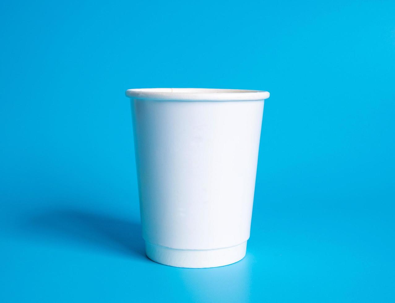 Front top view, disposable white coffee paper cup white with hot black coffee americano, no sugar milk, ready to drink, refreshing. aroma awake fresh to work placed on  Blue isolated background photo