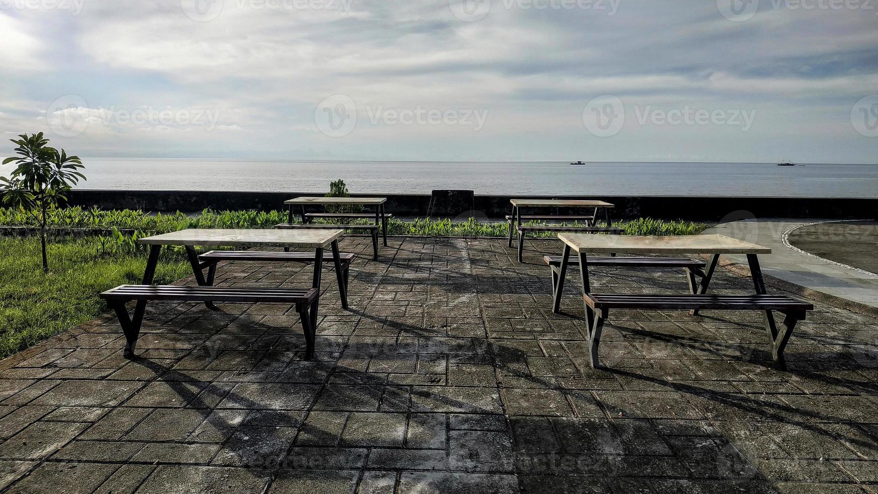 Rows of minimalist chairs and tables to relax enjoying the beach at Anjungan Vovasanggayu in Pasangkayu regency, Indonesia with a sea background photo