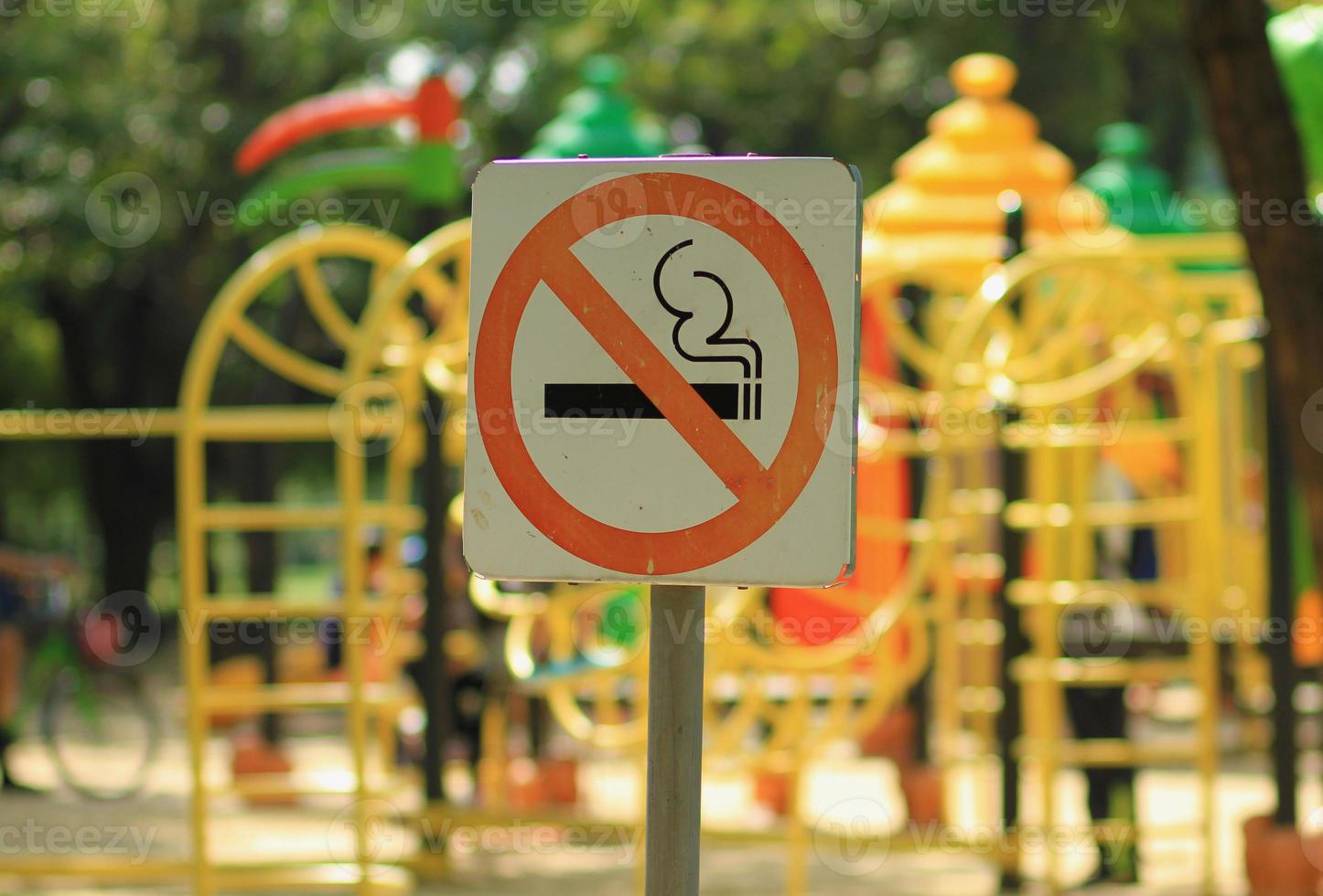 señal de prohibido fumar cerca del parque infantil en un parque público foto
