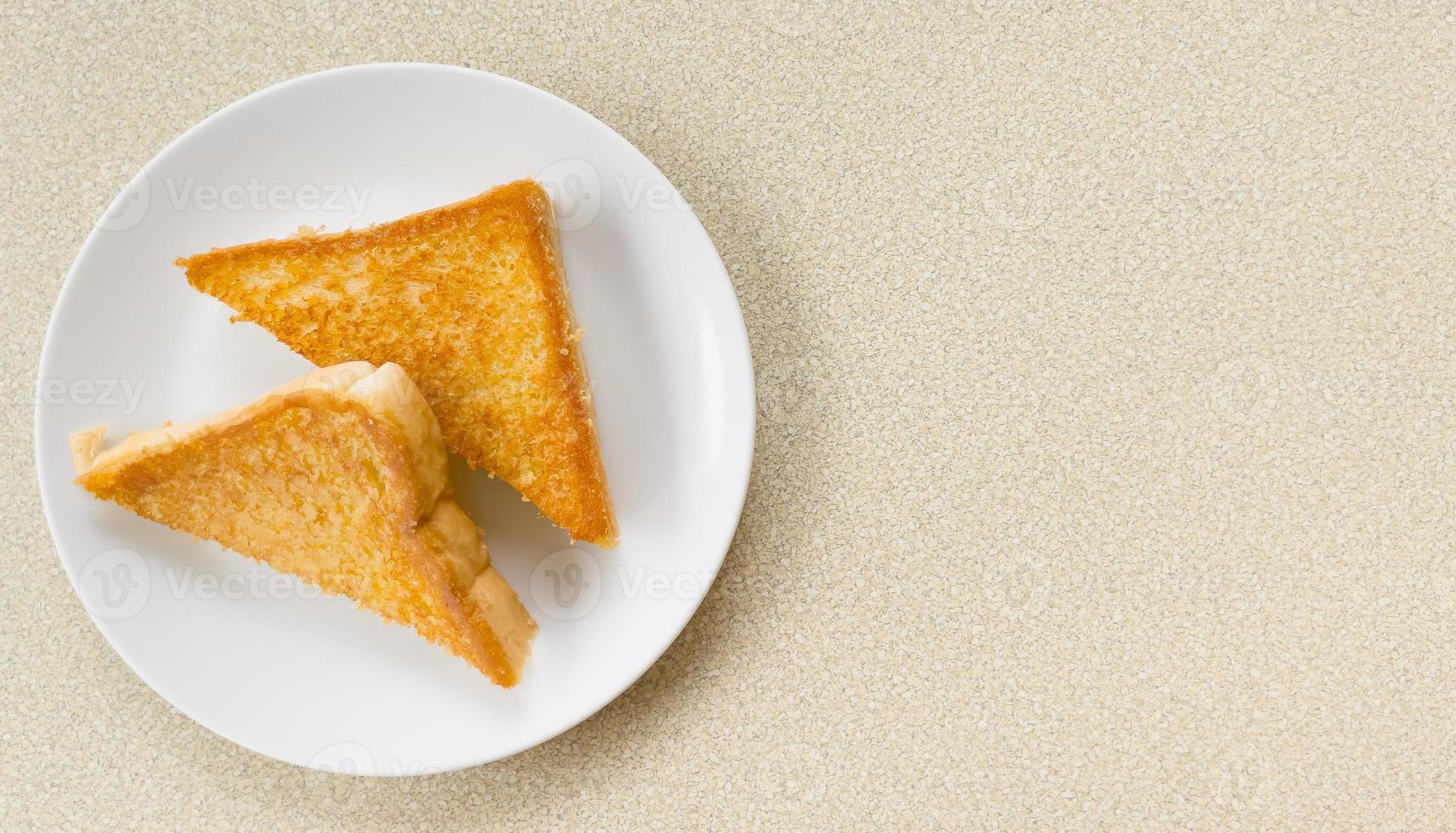 Two piece triangle slices of toasted bread made from white wheat flour and a slice of cheddar cheese in white plate. photo