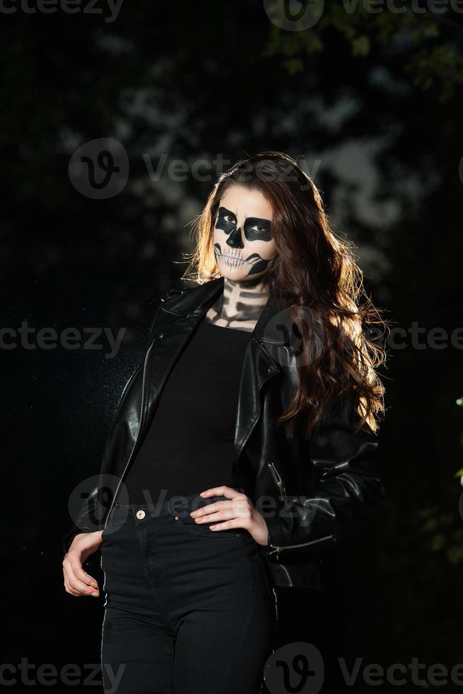 Halloween Vampire Woman portrait over scary night background. Vampire makeup Fashion Art design. Model girl in Halloween costume and make up. photo