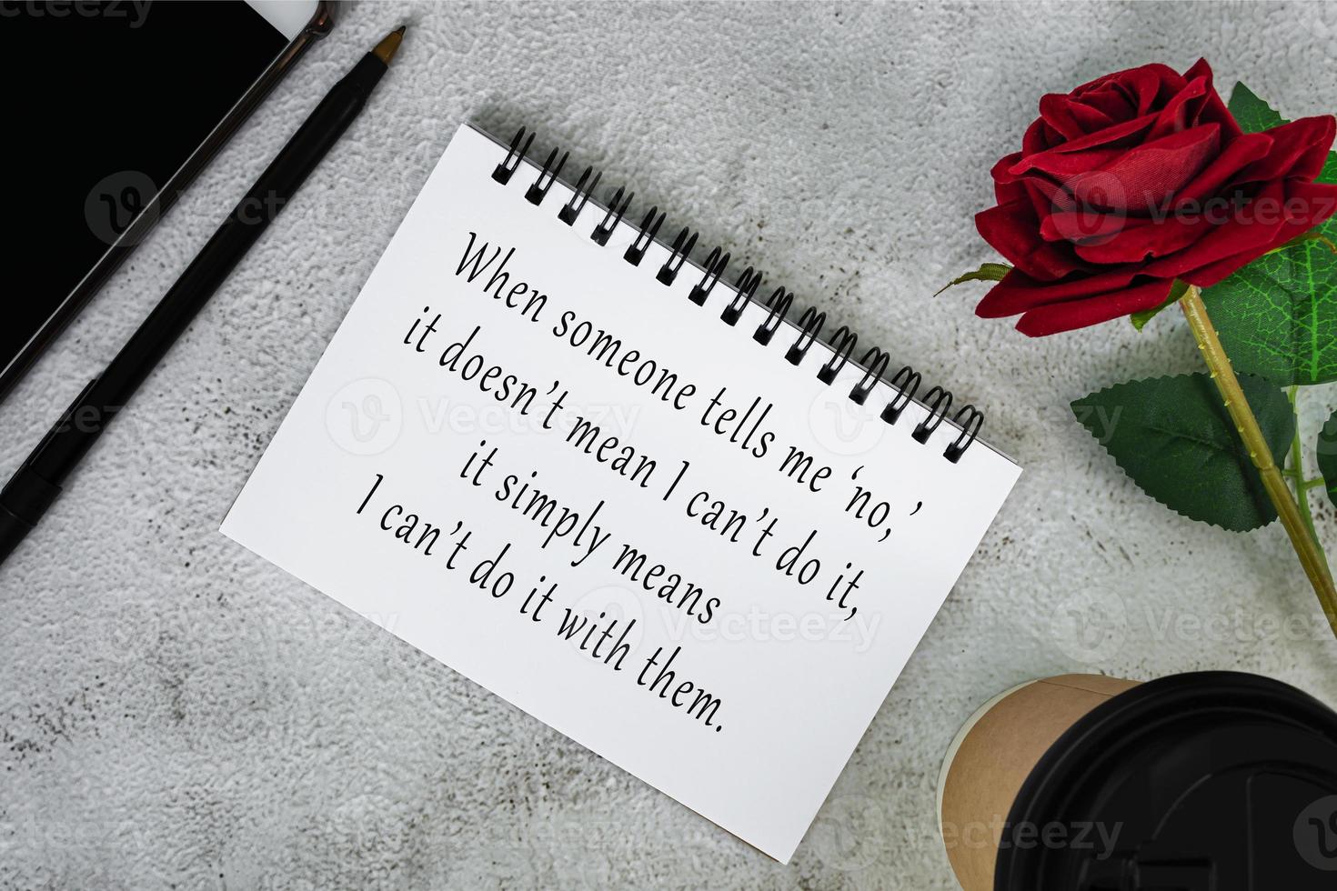 Motivational and inspirational quote on a note book on white marble table. photo
