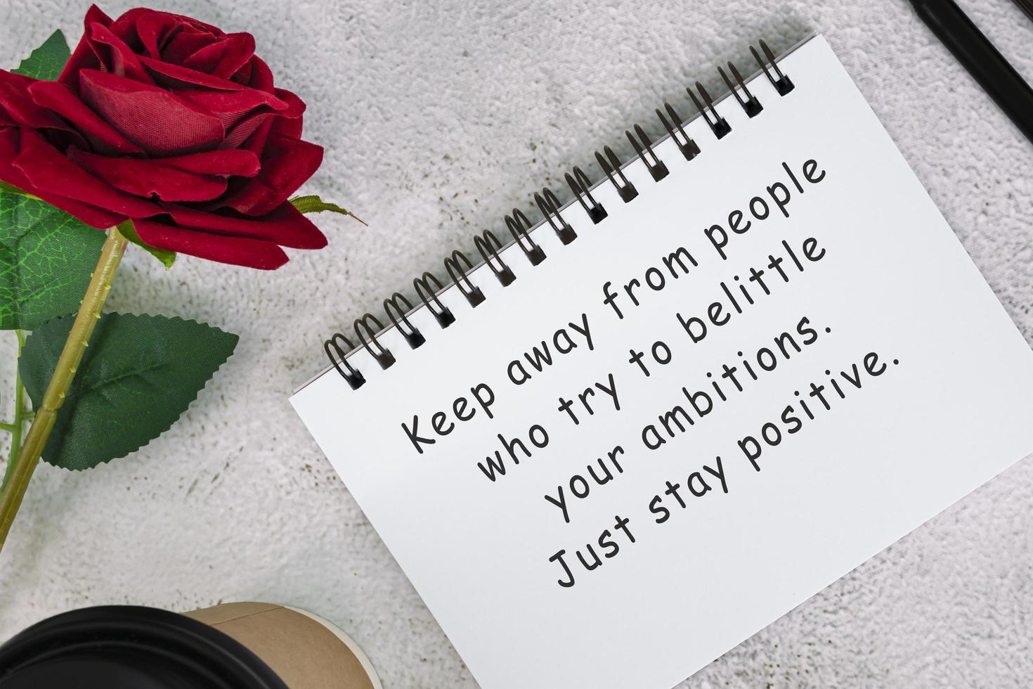 Motivational quote on a note book with roses on a desk. photo