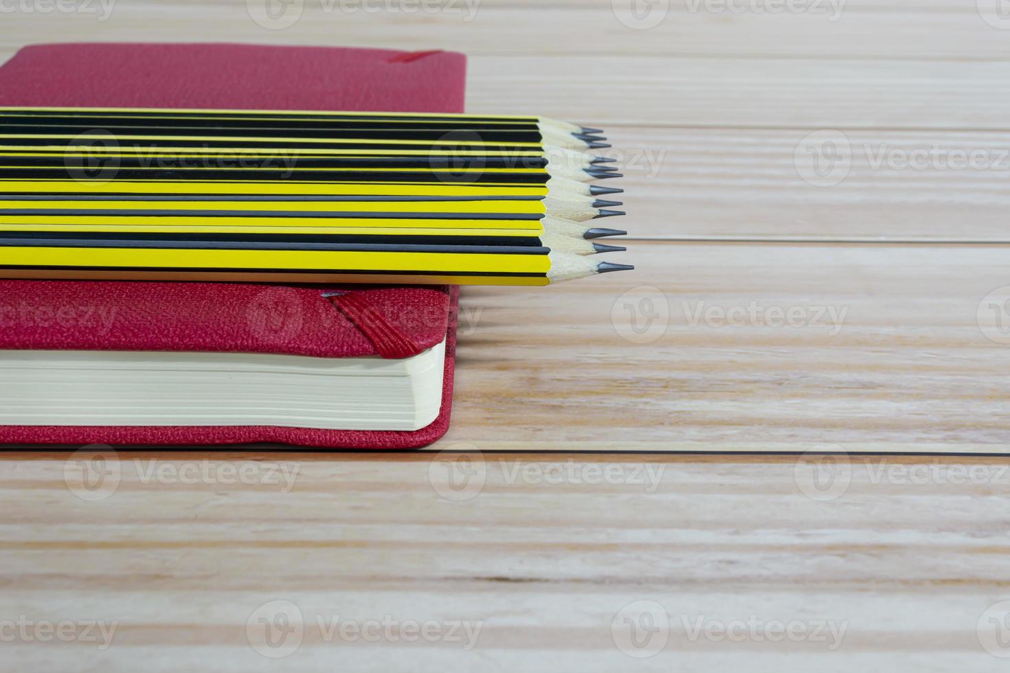 Wooden 2b pencils lying on red note book on wooden table. Copy space. photo