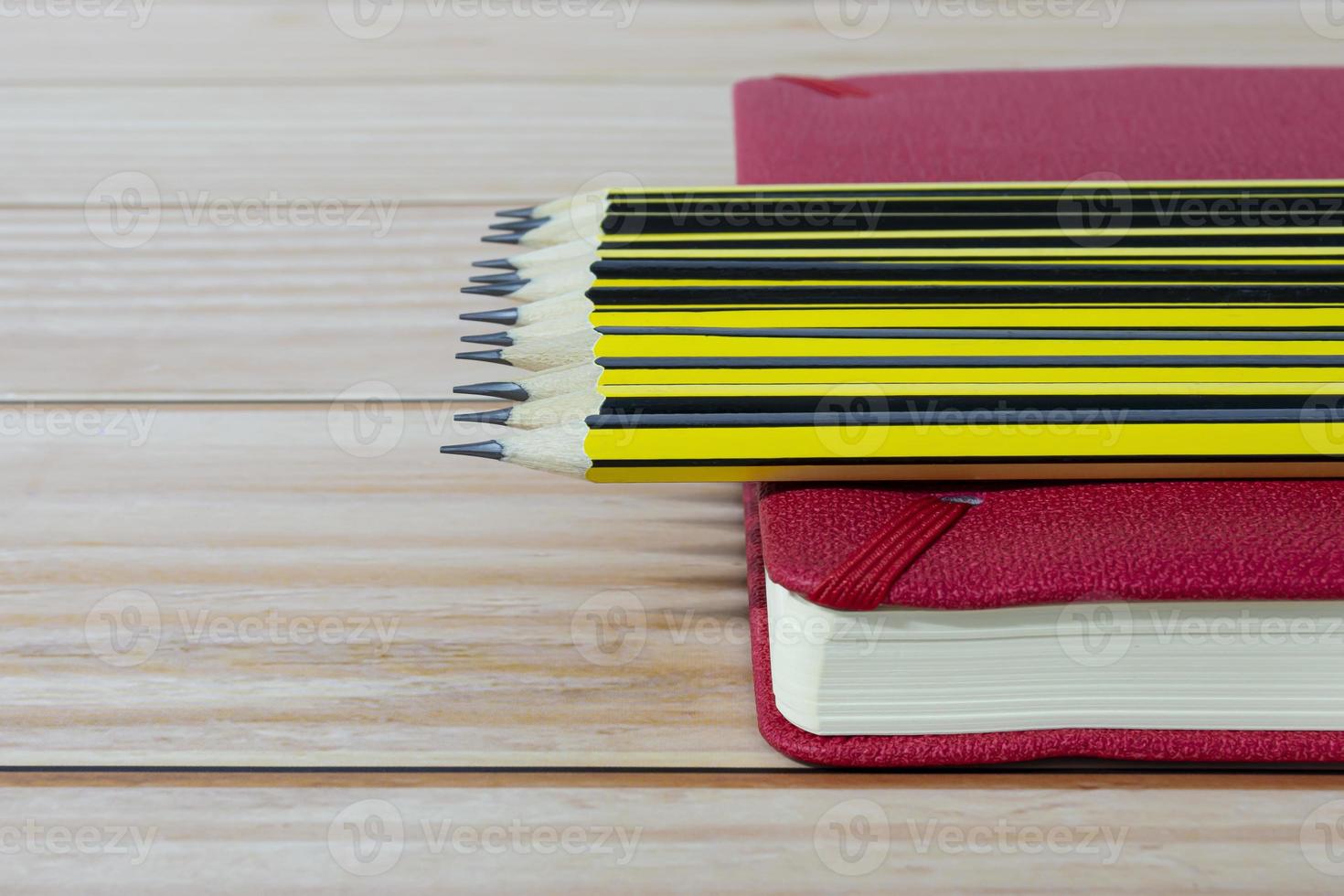 Wooden 2b pencils lying on red note book on wooden table. Copy space. photo