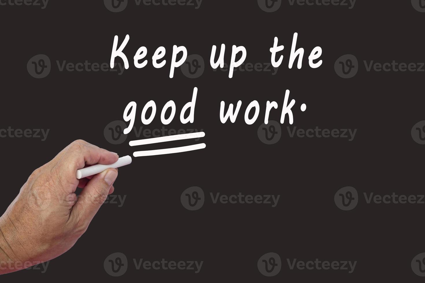 Male hand writes in white chalk pencil the word KEEP UP THE GOOD WORK. photo