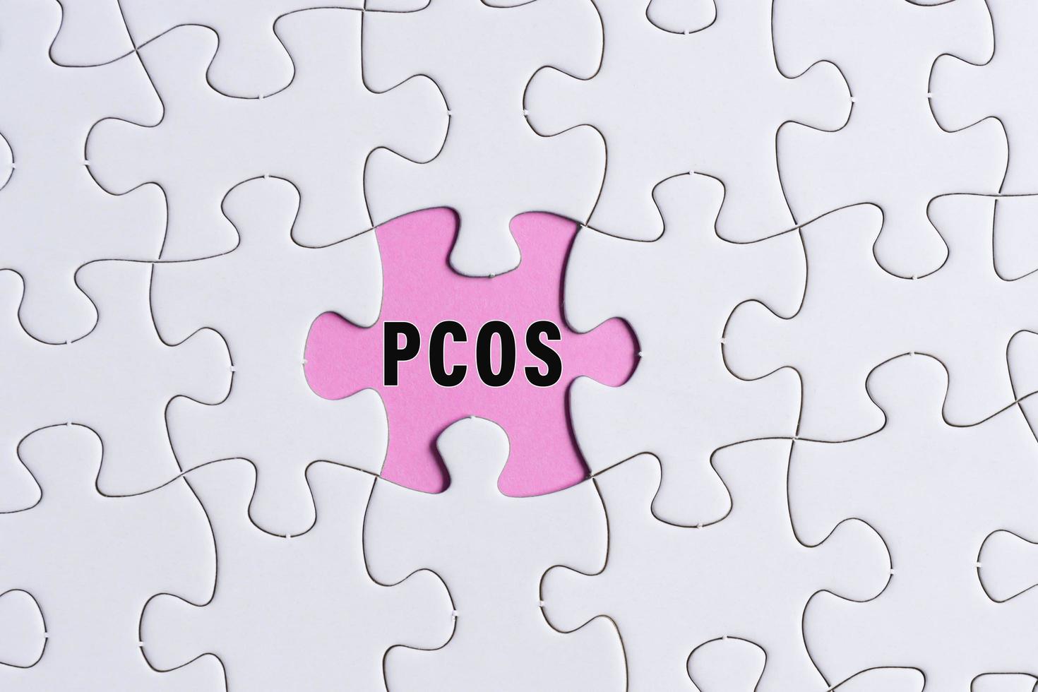 PCOS text on white jigsaw puzzle over pink background. Health Care concept. photo