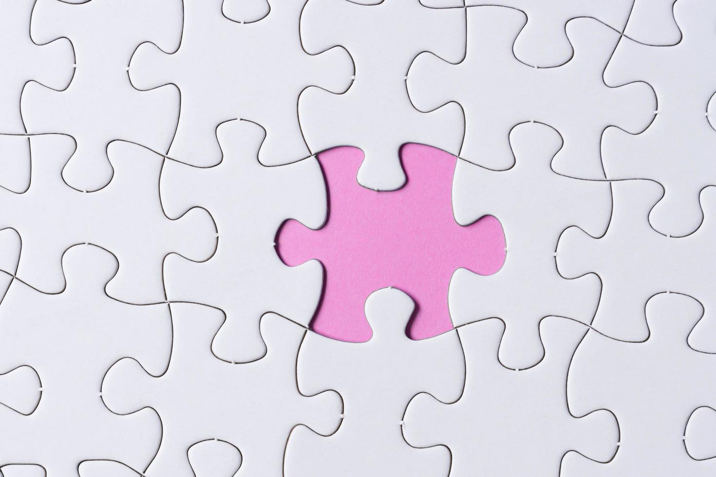 Piece of jigsaw puzzle on pink paper. Flat lay, Directly above. photo