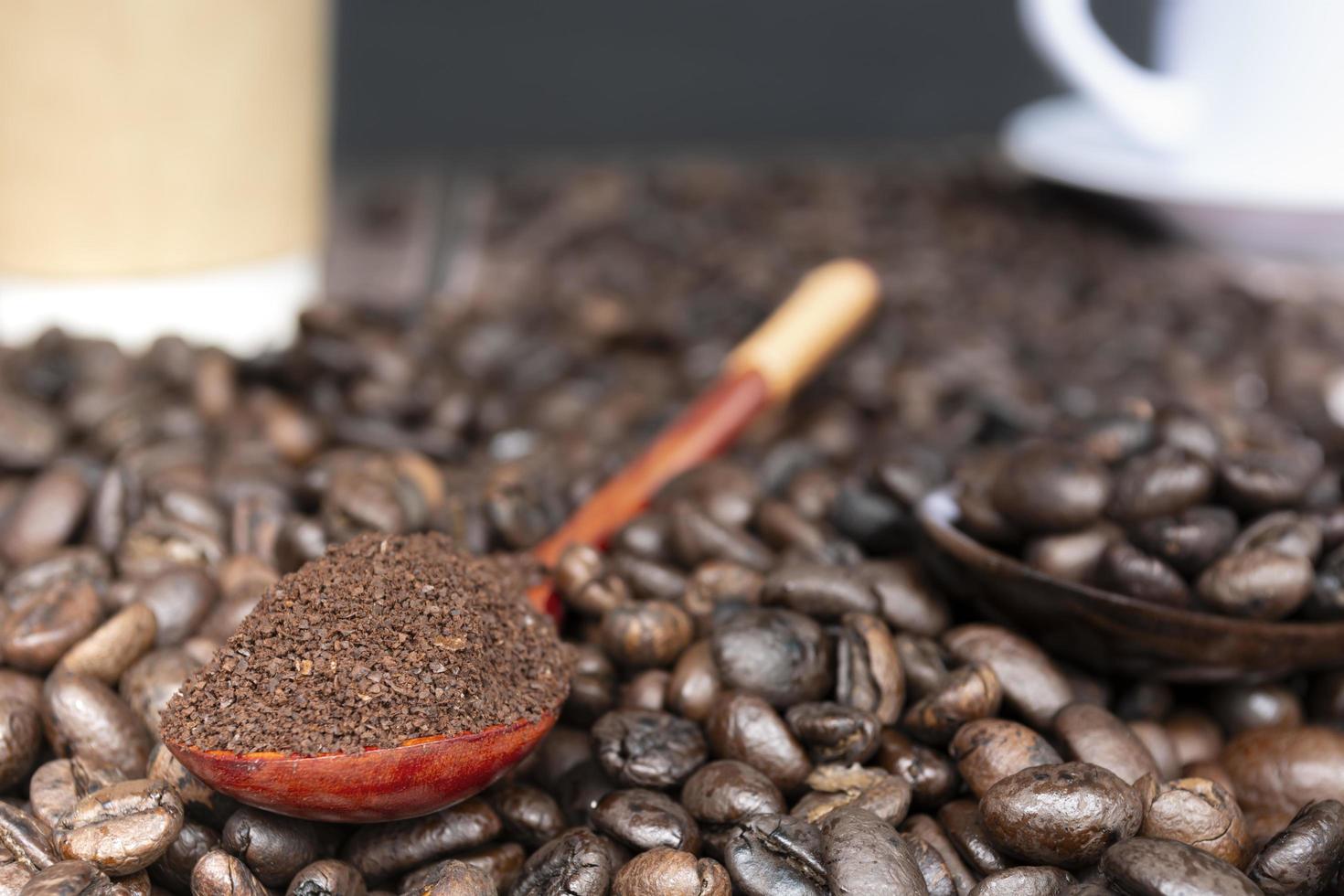 Roasted coffee beans and coffee powder or ground coffee in wooden spoon. photo