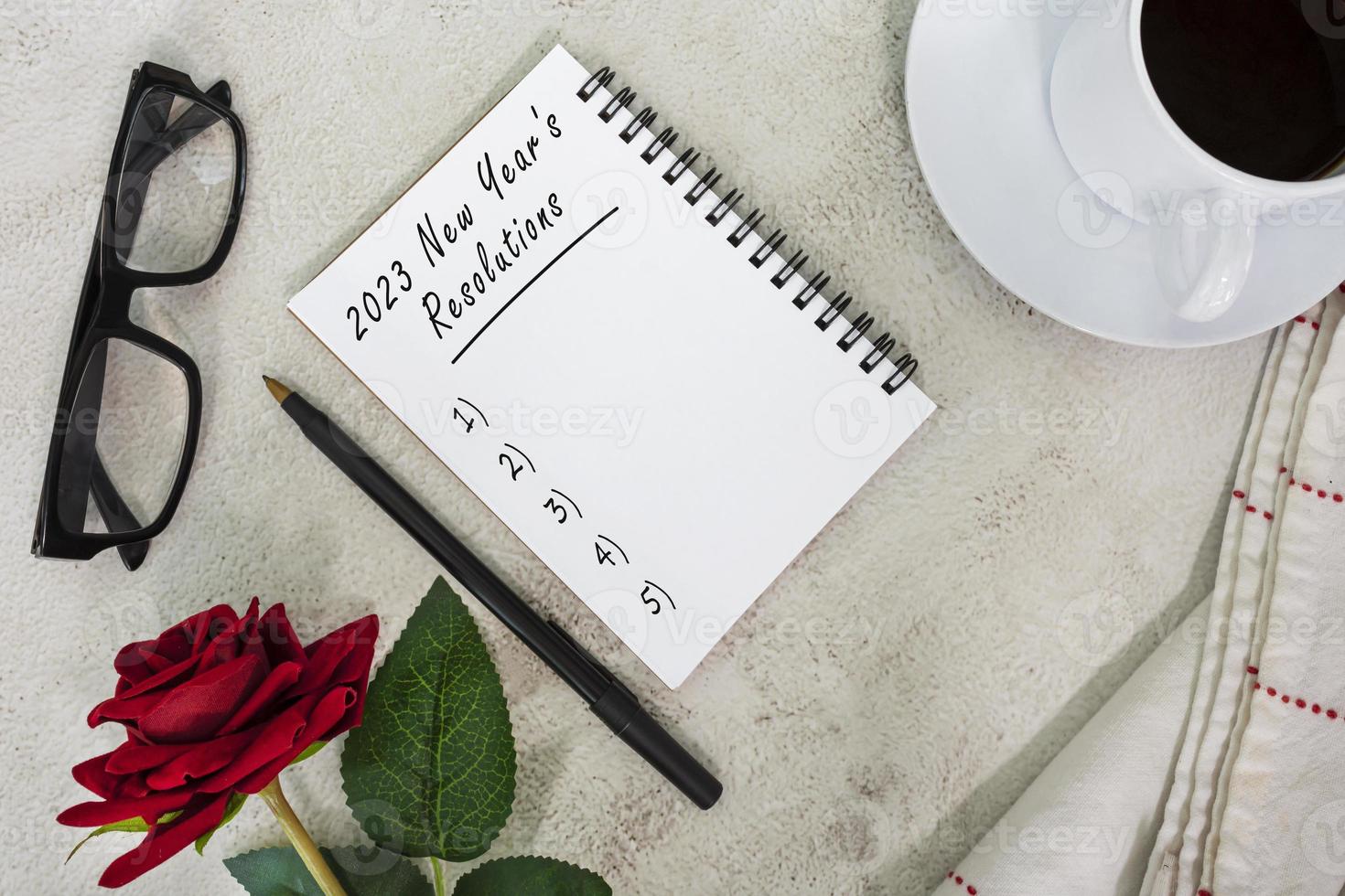 2023 New Year's Resolutions written on notebook on white marble table. photo