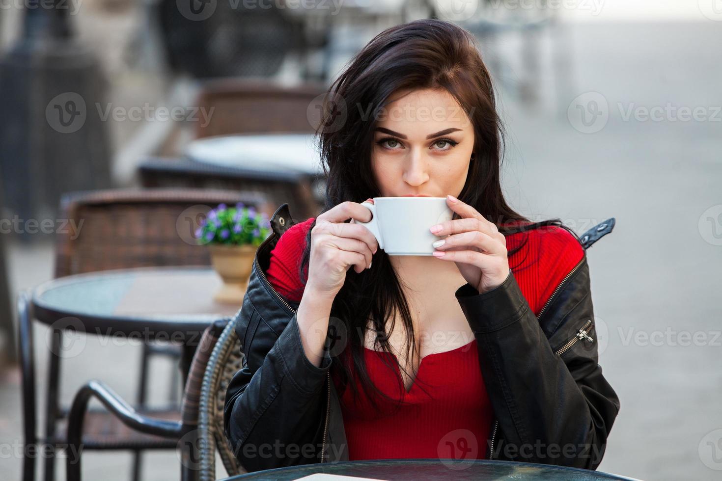 Young stylish woman drinking coffee in a city street.Stylish hipster girl drinking coffee in street. Outdoors fashion portrait of young beautiful girl drinking coffee. photo