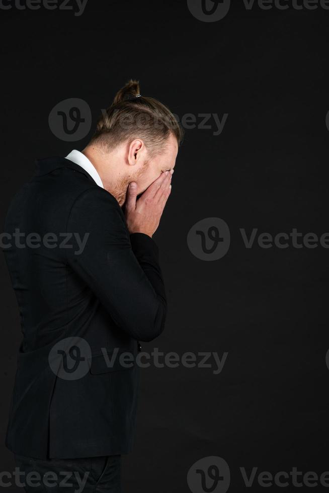 concepto de negocio y fracaso. hombre desesperado y de negocios con traje negro sobre fondo negro aislado. hombre inteligente y de mediana edad llorando con fracaso foto