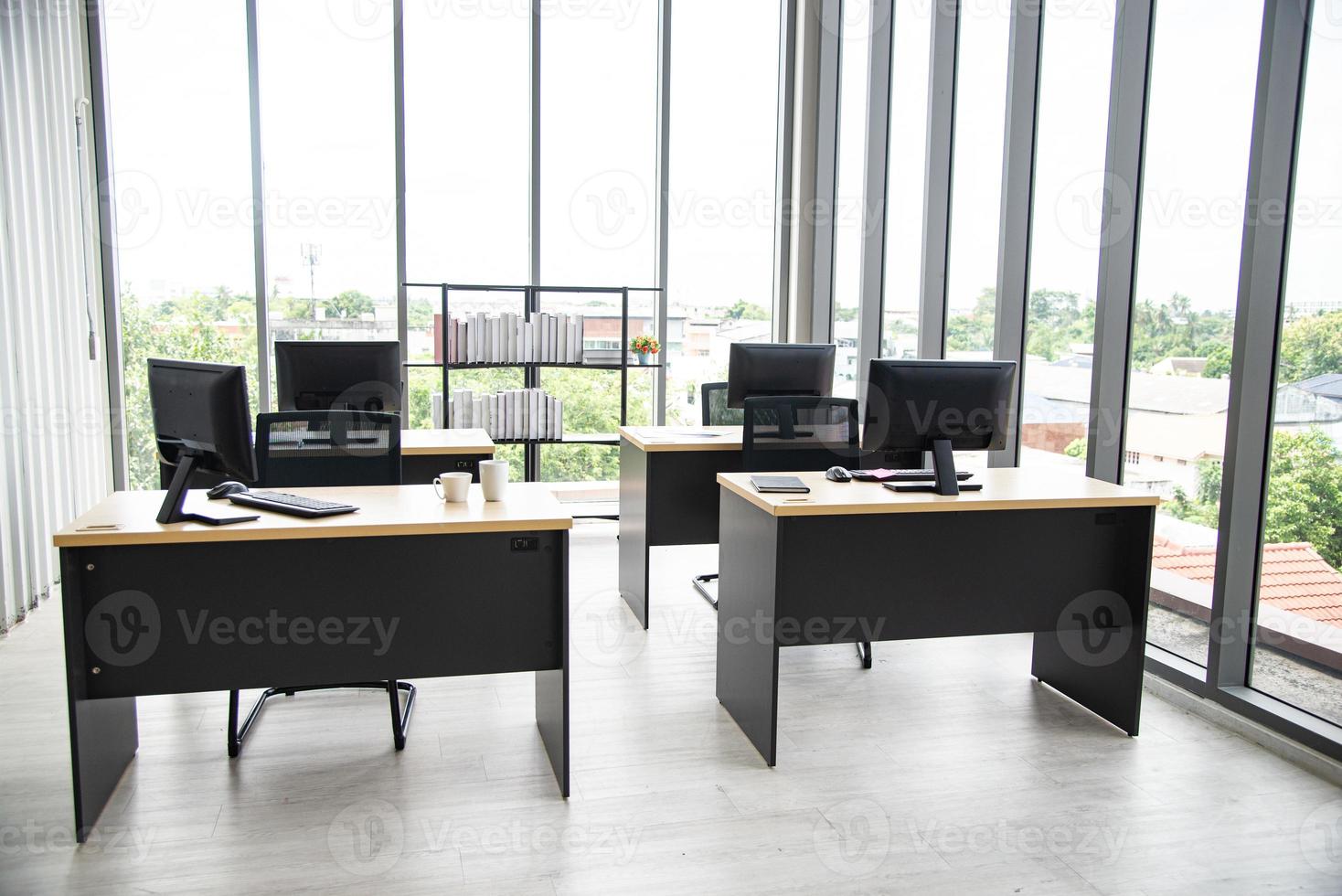 Modern office interior design with table computer monitor notebook and big glass window around the room without people photo