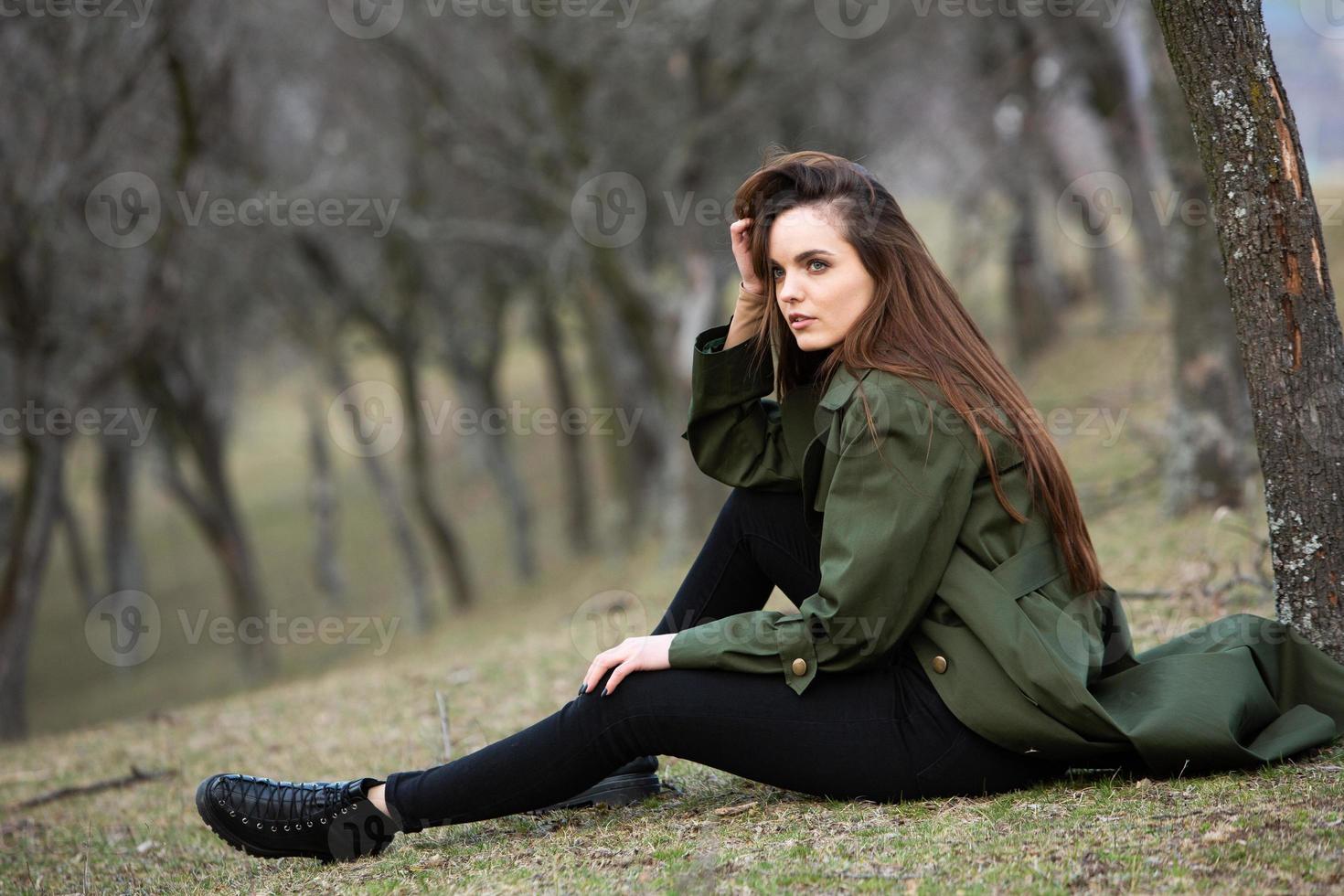 Image of young beautiful woman wearing rain jacket in cold weather. Thinker european girl in spring nature. photo