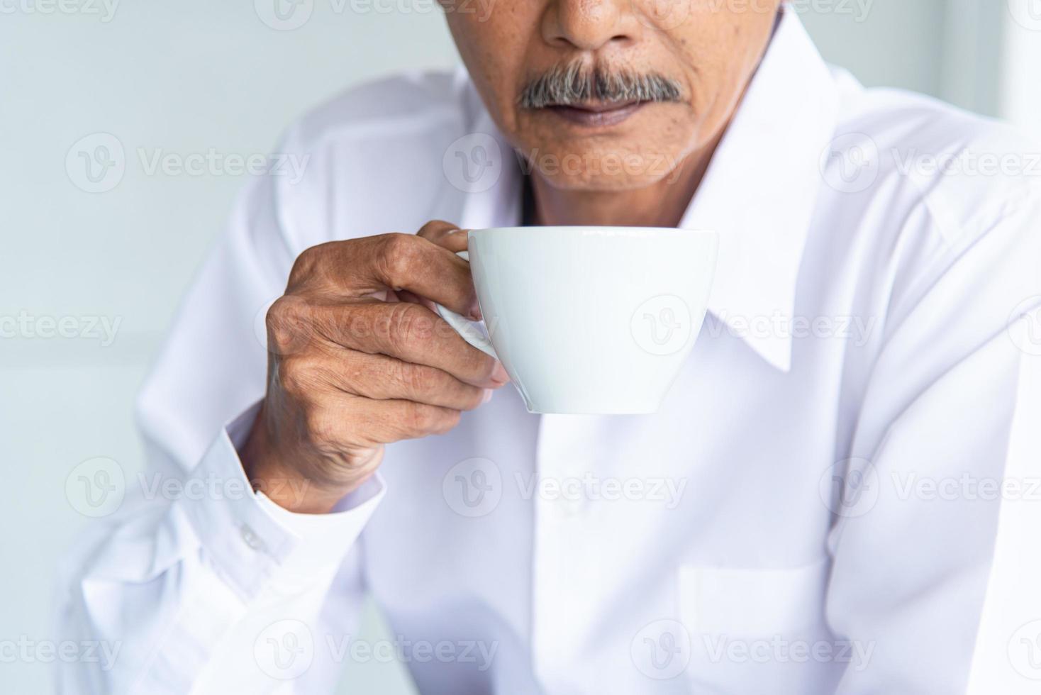 Asian Business old man  with white shirt drinking coffee in the meeting room at the office photo