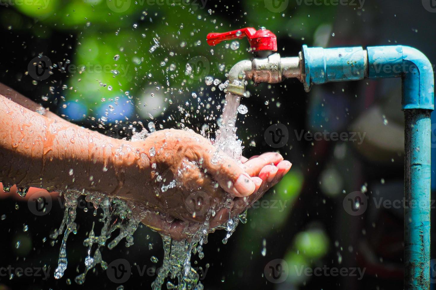 Water concept in everyday life. Hands supporting the water flowing from the faucet. water splashing from the tap photo