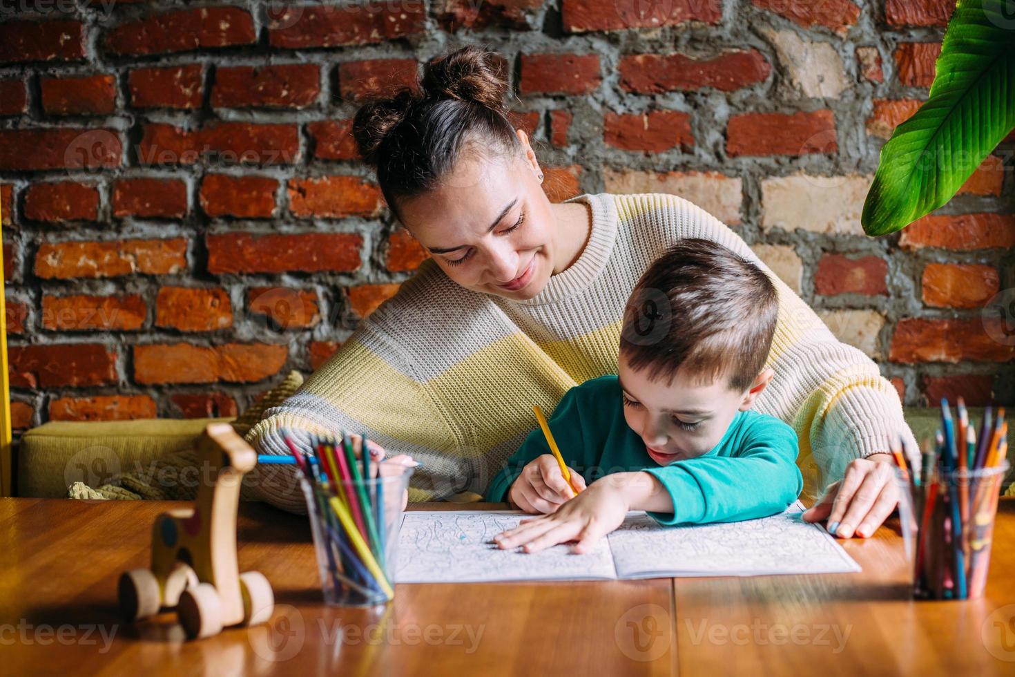 Child and adult are drawing a coloring book. photo