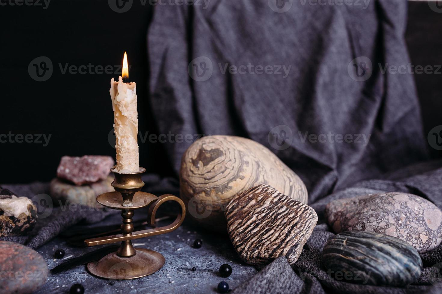 Burning candle and stones on the witch table. Occult, esoteric concept. photo