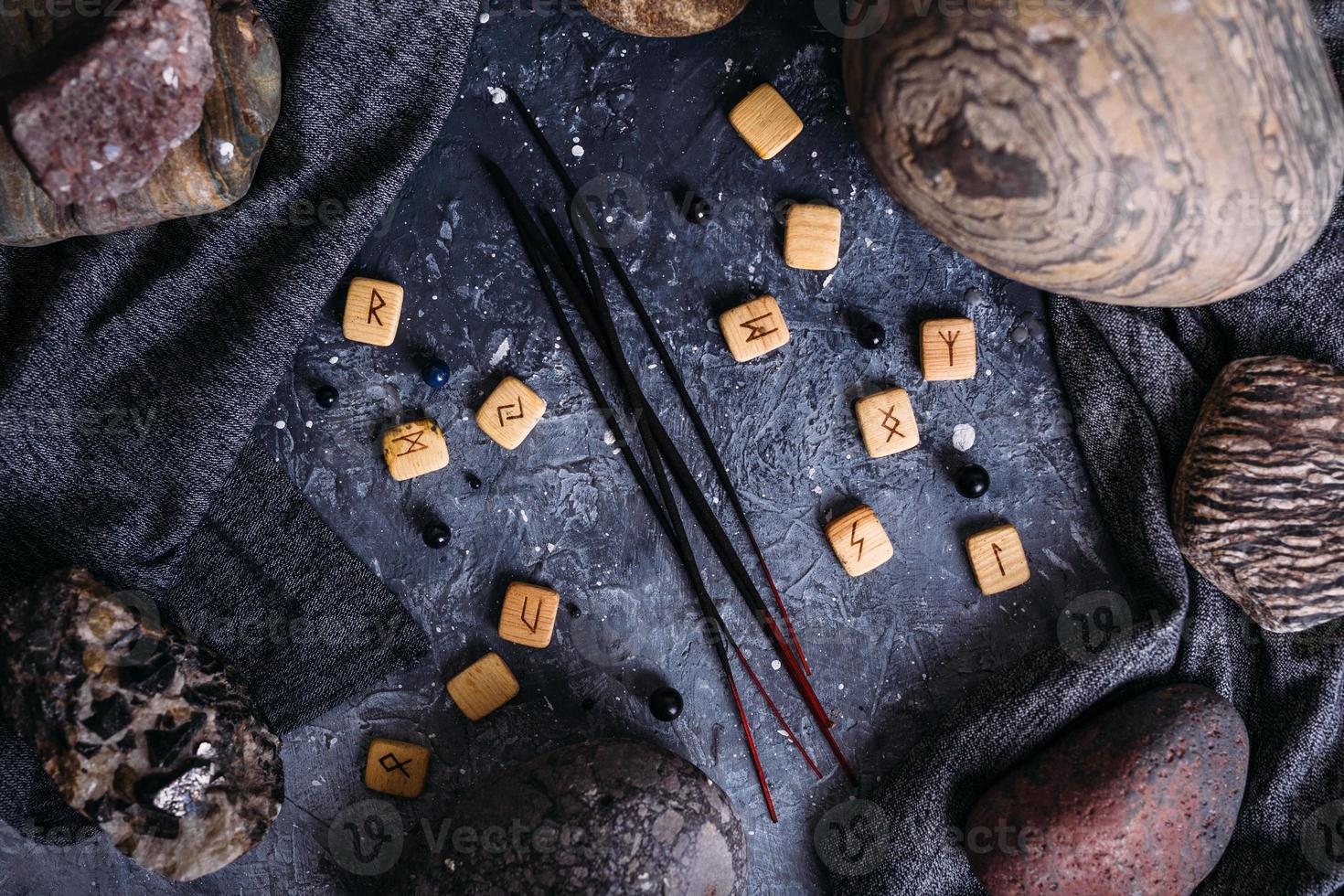 Incense sticks among the gloomy and esoteric paraphernalia - runes, stones. photo