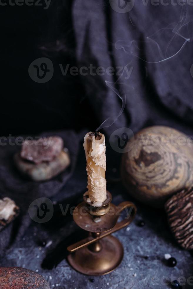 vela apagada, jarra y piedras en la mesa de brujas. foto