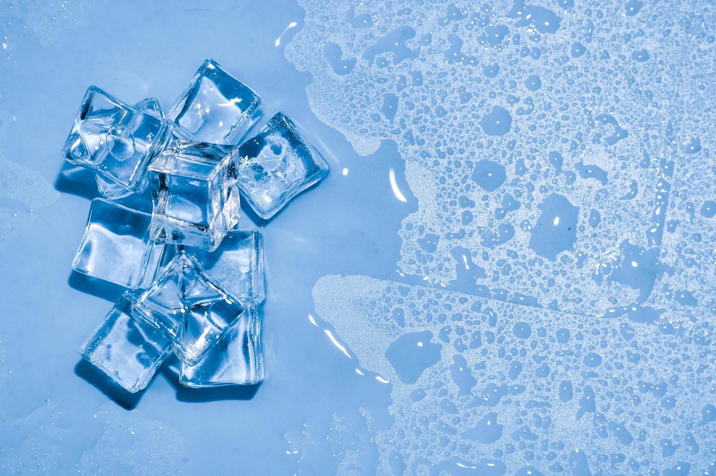 cubitos de hielo sobre fondo azul de estudio. el concepto de frescura con frialdad de cubitos de hielo. foto