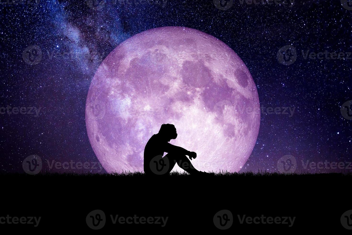 Desperate and lonely man in the background of the moon at night. Desperate, heartbreaking, and lonely concepts photo