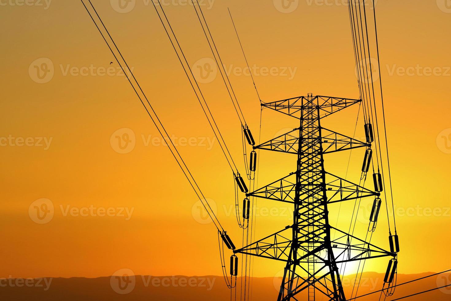 Silhouette of high voltage poles with electric wires. Silhouette of high voltage power line cables in an orange evening sunset. Steel structure of electric poles. electric power transmission concept photo