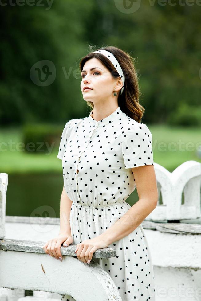 Woman's portrait with a hair moving in the wind.  portrait of young beautiful Russian brunette girl at summer green park. European white woman in dress. photo